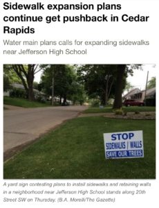 Gazette headline that reads: Sidewalk expansion plans continue to get pushback in Cedar Rapids, with a photo that says “STOP SIDEWALKS/WALLS SAVE OUR TREES”